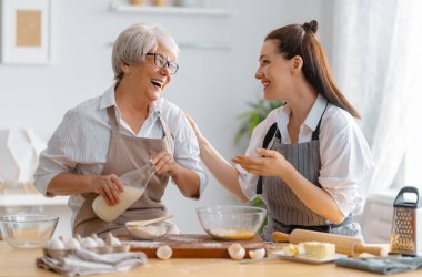 Mutfakta mutlu bir aile. Anne ve yetişkin kızı pasta hazırlıyorlar..