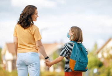 Ortaokulun ebeveyni ve öğrencisi el ele gidiyor. Sırt çantalı kadın ve kız. Dersler başlıyor.. 