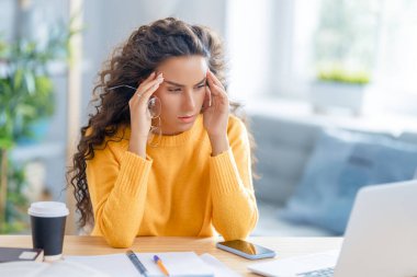 İnternette okuyan genç bir iş kadını, Webinar izliyor, dizüstü bilgisayarda podcast yapıyor ve başı ağrıyor. E-öğrenme kavramı.