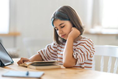 Okula dönelim. Çocuk masada oturuyor. Ödev yapan ya da online eğitim alan kız.