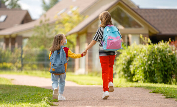 Pupils going to school. Girls with backpacks outdoors. Beginning of lessons. 