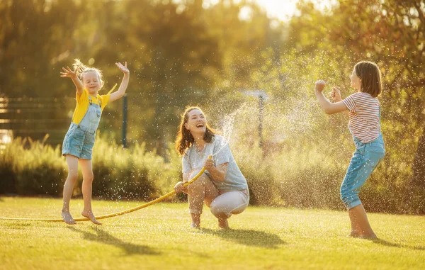 Família Feliz Brincando Quintal Mãe Polvilhando Seus Filhos Dia Quente — Fotografia de Stock