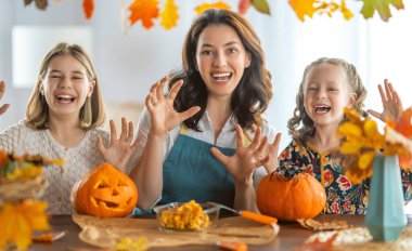 Mutlu Cadılar Bayramı! Anne ve kızları balkabağı oyuyor. Aile tatili için hazırlanıyor.