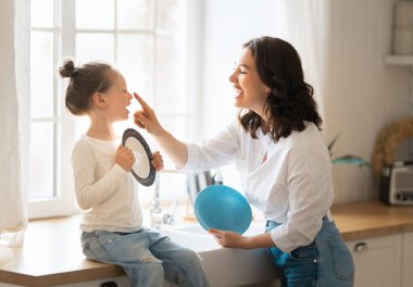 Mutlu bir gün! Anne ve kızı mutfakta oynuyorlar, gülümsüyorlar. Aile tatili ve birliktelik. 