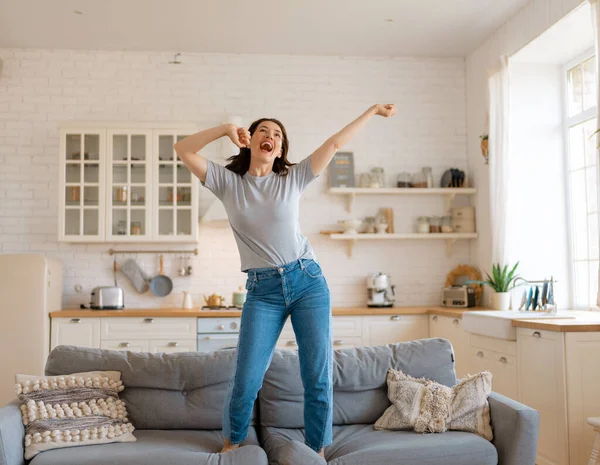 Young woman jumping on the sofa at home.