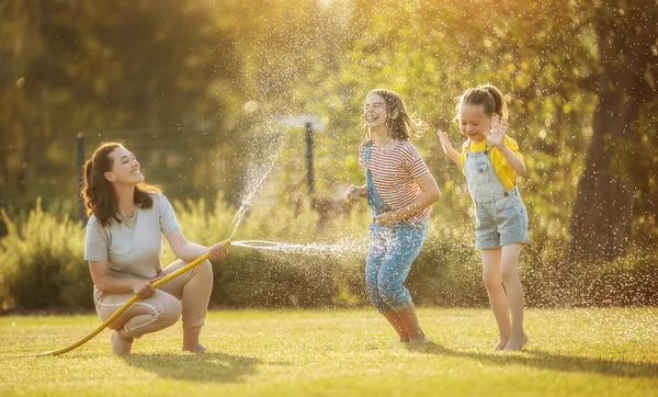 Família Feliz Brincando Quintal Mãe Polvilhando Seus Filhos Dia Quente — Fotografia de Stock