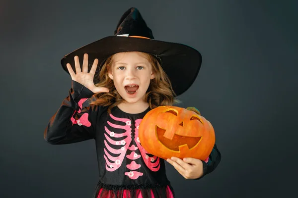 楽しいハロウィンをお過ごし下さい 黒い壁の背景に魔女の衣装でかわいい笑う女の子 — ストック写真