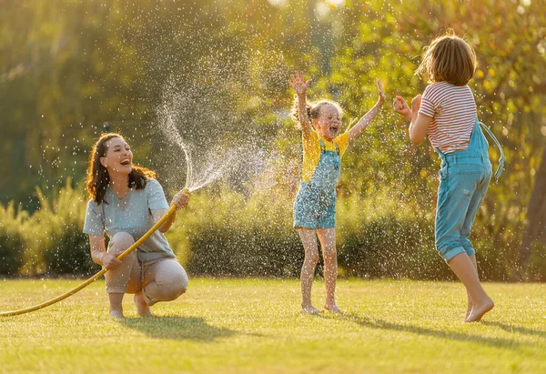 Família Feliz Brincando Quintal Mãe Polvilhando Seus Filhos Dia Quente — Fotografia de Stock