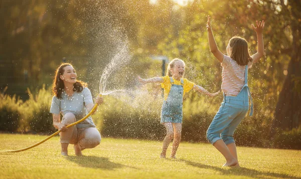 Família Feliz Brincando Quintal Mãe Polvilhando Seus Filhos Dia Quente — Fotografia de Stock