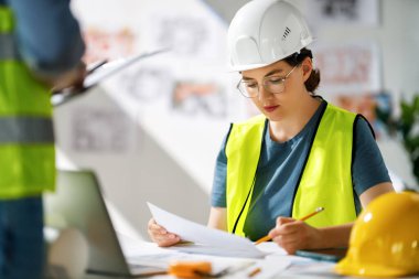 İnşaat alanında planlar üzerinde çalışan mimarlardan oluşan bir ekip..