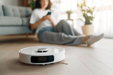 Ahşap zeminde beyaz robot elektrikli süpürge. Akıllı temizlik teknolojisi