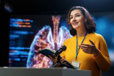 A young woman is giving a presentation at a medical conference.
