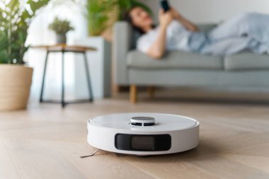 Ahşap zeminde beyaz robot elektrikli süpürge. Akıllı temizlik teknolojisi