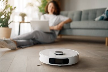 Ahşap zeminde beyaz robot elektrikli süpürge. Akıllı temizlik teknolojisi