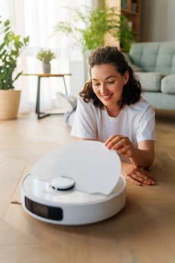 Ahşap zeminde beyaz robot elektrikli süpürge. Akıllı temizlik teknolojisi