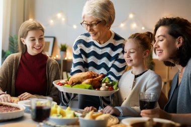 Şükran Günü, Sonbahar ziyafeti. Masada oturup bayramı kutlayan mutlu bir aile. Geleneksel yemek. Büyükanne, anne ve çocuklar. 