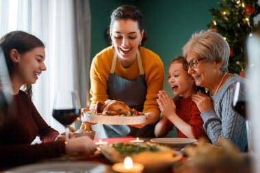 Mutlu noeller. Mutlu aile evde yemek yiyor. Kutlama tatili ve ağacın yakınındaki birliktelik.