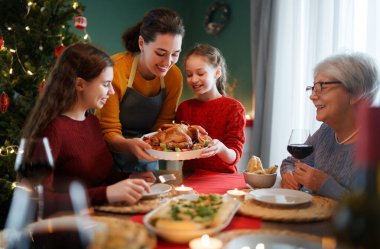Mutlu noeller. Mutlu aile evde yemek yiyor. Kutlama tatili ve ağacın yakınındaki birliktelik.