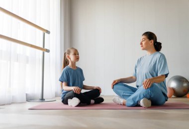 Çocuk fizik tedaviden geçiyor. Kız, doktorun gözetiminde egzersizler yapıyor..