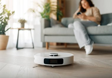 Ahşap zeminde beyaz robot elektrikli süpürge. Akıllı temizlik teknolojisi