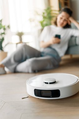 Ahşap zeminde beyaz robot elektrikli süpürge. Akıllı temizlik teknolojisi