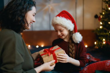 Mutlu Noeller, mutlu tatiller. Anne ve kızı ağacın yanında hediyelerle..