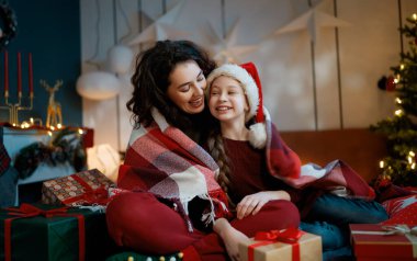 Mutlu Noeller, mutlu tatiller. Anne ve kızı ağacın yanında hediyelerle..