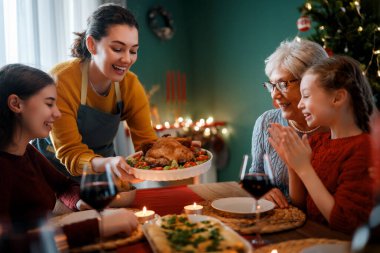 Mutlu noeller. Mutlu aile evde yemek yiyor. Kutlama tatili ve ağacın yakınındaki birliktelik.