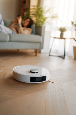 Ahşap zeminde beyaz robot elektrikli süpürge. Akıllı temizlik teknolojisi