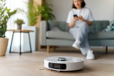 Ahşap zeminde beyaz robot elektrikli süpürge. Akıllı temizlik teknolojisi