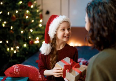 Mutlu Noeller, mutlu tatiller. Anne ve kızı ağacın yanında hediyelerle..