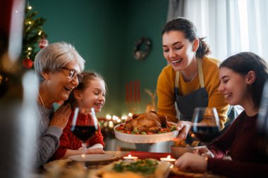 Mutlu noeller. Mutlu aile evde yemek yiyor. Kutlama tatili ve ağacın yakınındaki birliktelik.