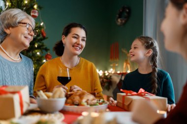 Mutlu noeller. Mutlu aile evde yemek yiyor. Kutlama tatili ve ağacın yakınındaki birliktelik.