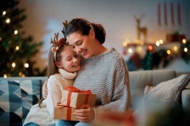 Mutlu Noeller, mutlu tatiller. Anne ve kızı ağacın yanında hediyelerle..