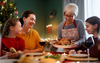 Mutlu noeller. Mutlu aile evde yemek yiyor. Kutlama tatili ve ağacın yakınındaki birliktelik.