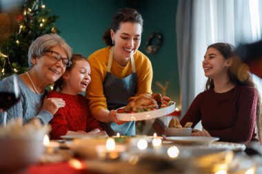 Mutlu noeller. Mutlu aile evde yemek yiyor. Kutlama tatili ve ağacın yakınındaki birliktelik.