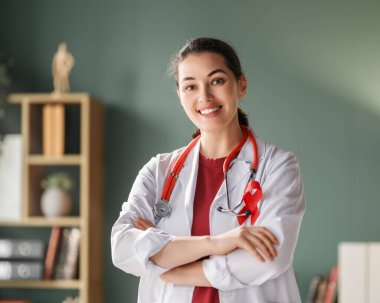 Kırmızı kurdeleli kadın doktor muayenehanede.