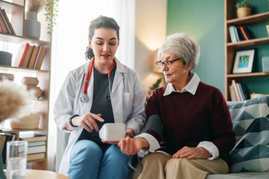 Doktor yaşlı bir kadına kan basıncını ölçüyor..