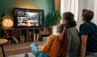 Mutlu aile birlikte vakit geçiriyor. Anne, baba ve çocuk televizyon seyrediyor, akşamları evde film seyrediyor..