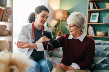 Doktor yaşlı bir kadına kan basıncını ölçüyor..