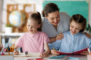 Okulda mutlu çocuklar ve öğretmen var. Sınıfta kadınlar ve çocuklar çalışıyor..