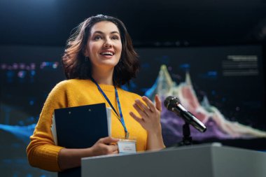 A young woman is giving a presentation at a conference.