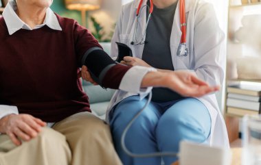 Doktor yaşlı bir kadına kan basıncını ölçüyor..