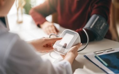 Doktor yaşlı bir kadına kan basıncını ölçüyor..