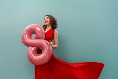 Gökyüzü duvarında elinde sekiz balonla güzel bir genç kız..