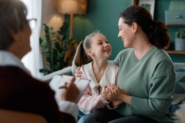 Mutlu bir anne ve kız terapi seansı sırasında samimi bir anı paylaşıyorlar. Gülüşleri ve yakın bağları aile danışmanlığında bulunan mutluluk ve desteği temsil ediyor. Ayarların sıcak atmosferi duygusal bağlantıyı güçlendirir..