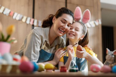 Paskalya yumurtalarını sıcak bir mutfakta boyarken anne ve kızın kaynaştığı neşeli bir an. Pembe tavşan kulağı takan küçük kız, Paskalya geleneklerini kutlarken annesiyle yürekten bir gülüşü paylaşıyor..