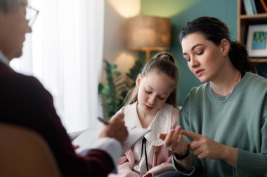 Şefkatli bir annenin ve genç kızının profesyonel bir terapistle terapi seansına katıldığı duygusal bir sahne. Destek ve beslenme ortamı, Menta 'yı çevreleyen konular için ideal anlayış, güven ve iletişimi vurguluyor.