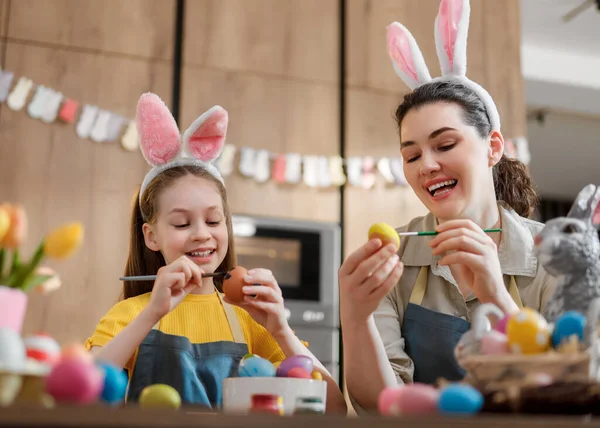 Neşeli anne-kız ikilisi tavşan kulağı takıyor, renkli Paskalya yumurtaları boyuyor. Sıcak bir mutfak ortamında tatil şenlikleri sırasında aile bağlarını ve yaratıcılığı yakalamak.