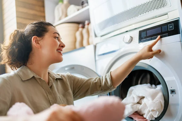 Sıcak bir çamaşır odasında çağdaş bir çamaşır makinesini çalıştıran neşeli genç kadın ev işlerinin keyfini çıkarıyor. Temizlik, verimlilik ve konforun altını çizerek çamaşırları yıkıyor, kusursuz bir ev rutinini kucaklıyor..